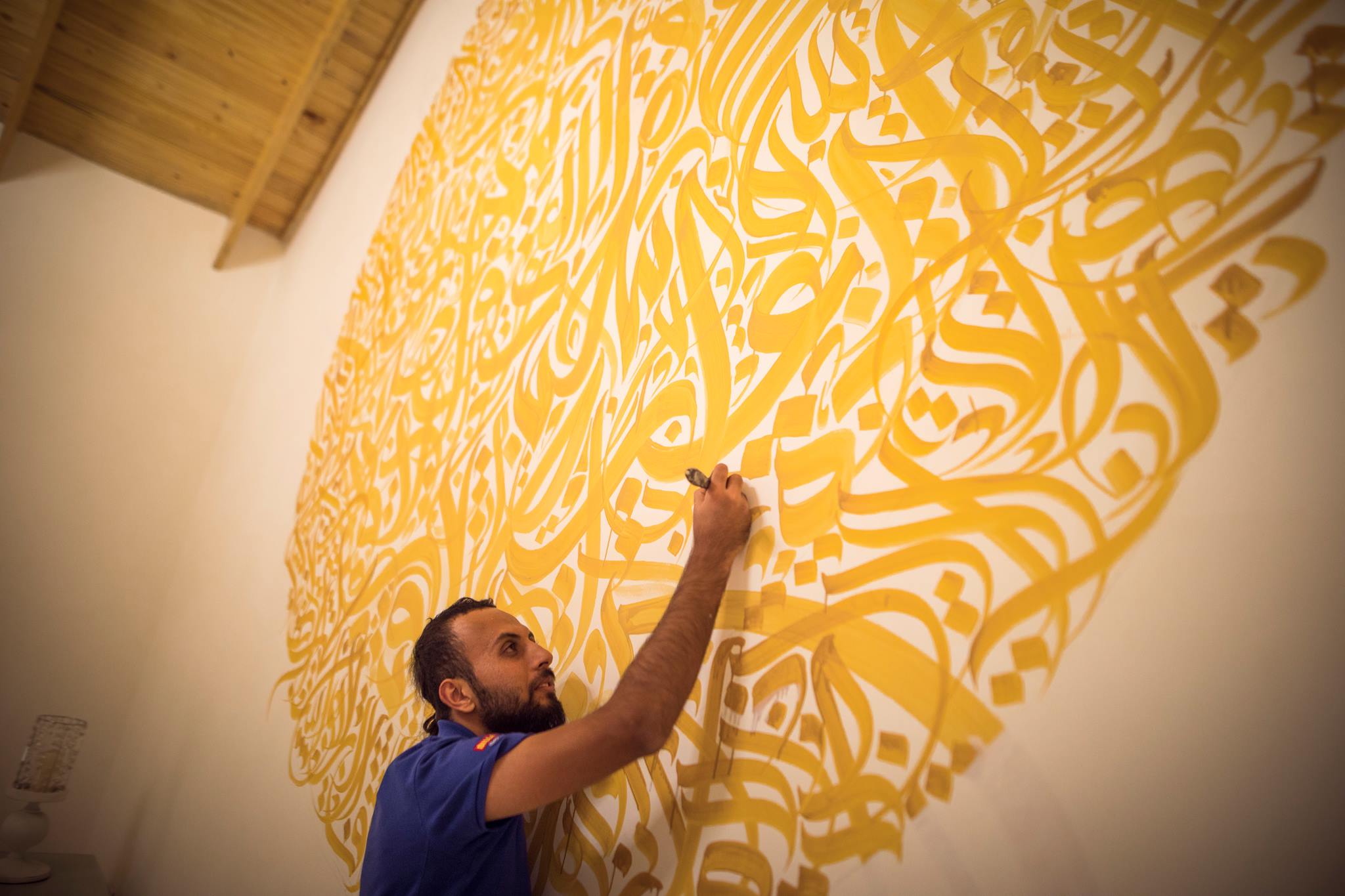 مجنون الخط العربي.. يرسم على أي سطح تصل إليه يداه، حتى أجساد الرياضيين كان لها حظ من ألوانه