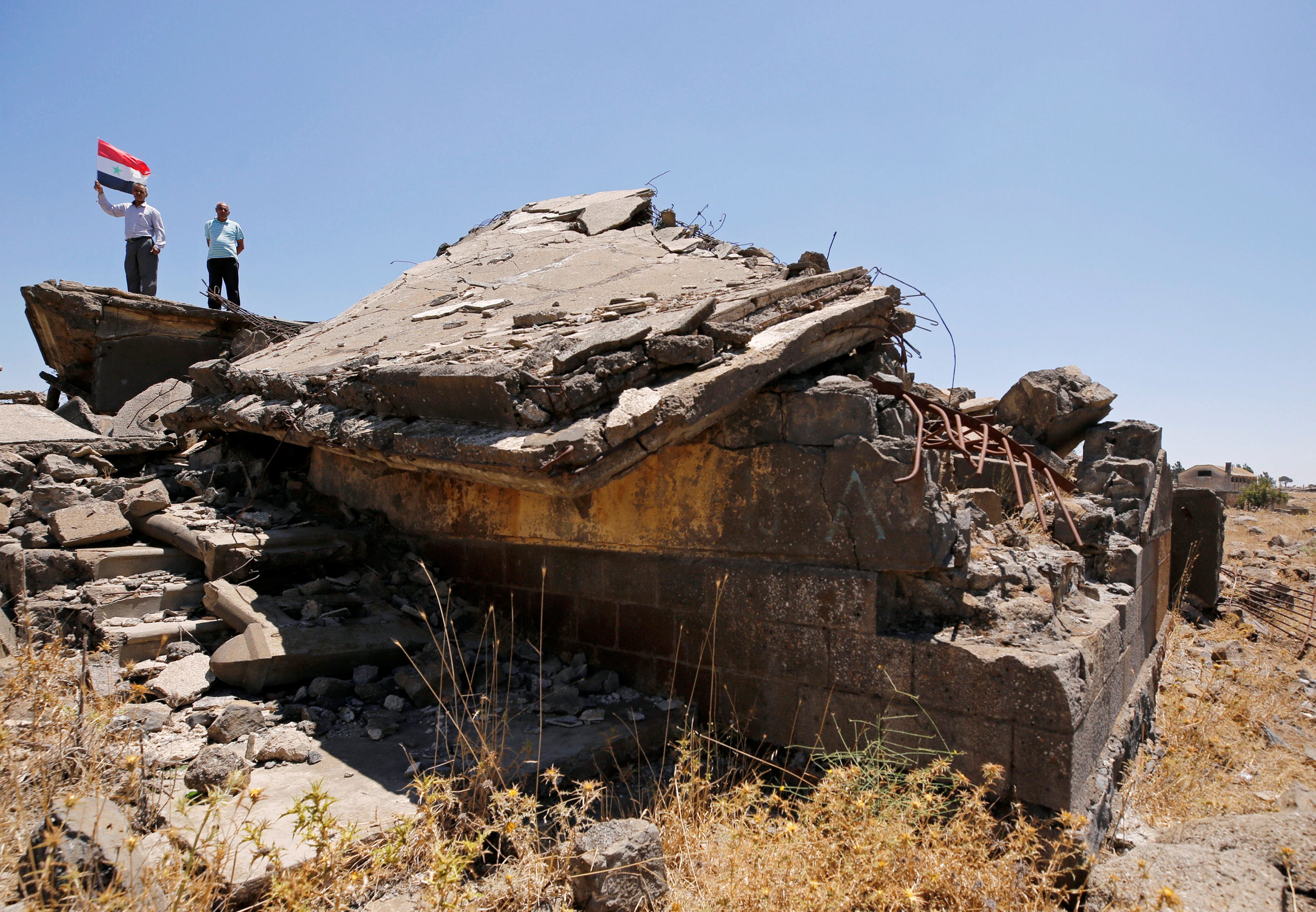 مواطن يرفع العلم السوري على أنقاض مباني حطمتها الحرب