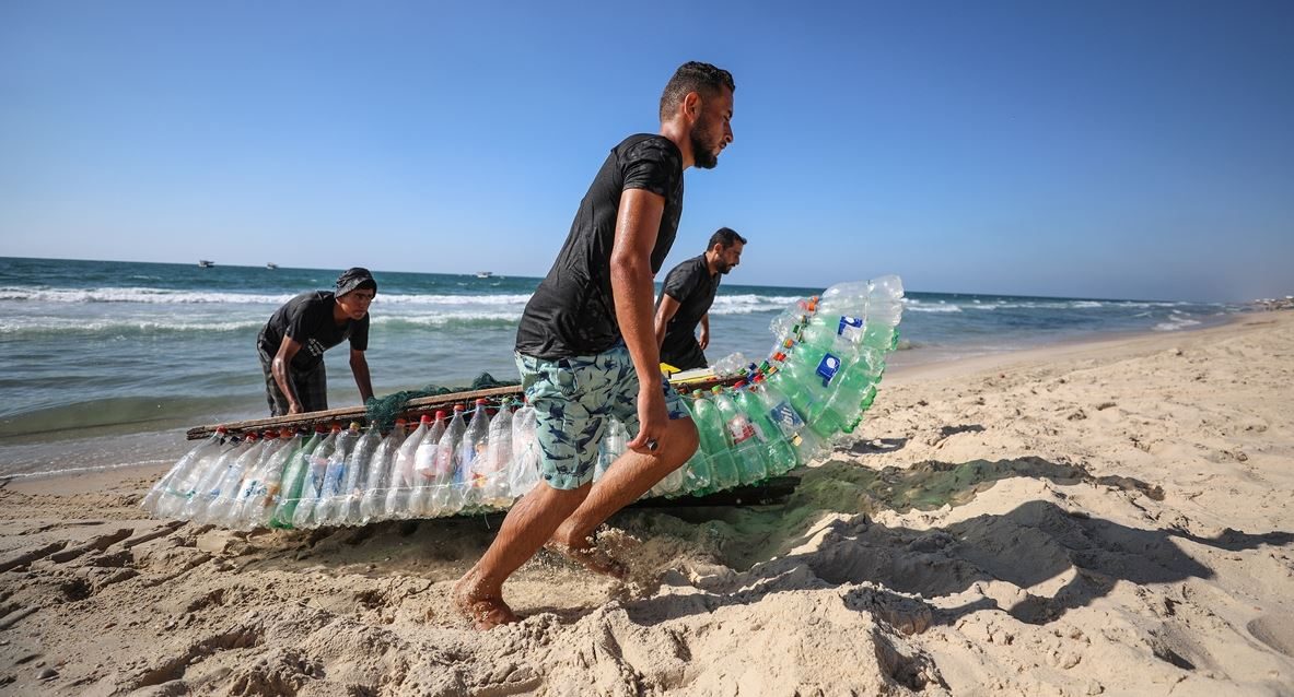 وسط استغراب الناس من حوله.. فلسطيني يُبحر على 700 عبوة بلاستيكية ليصطاد رزق عائلته، صور وفيديو