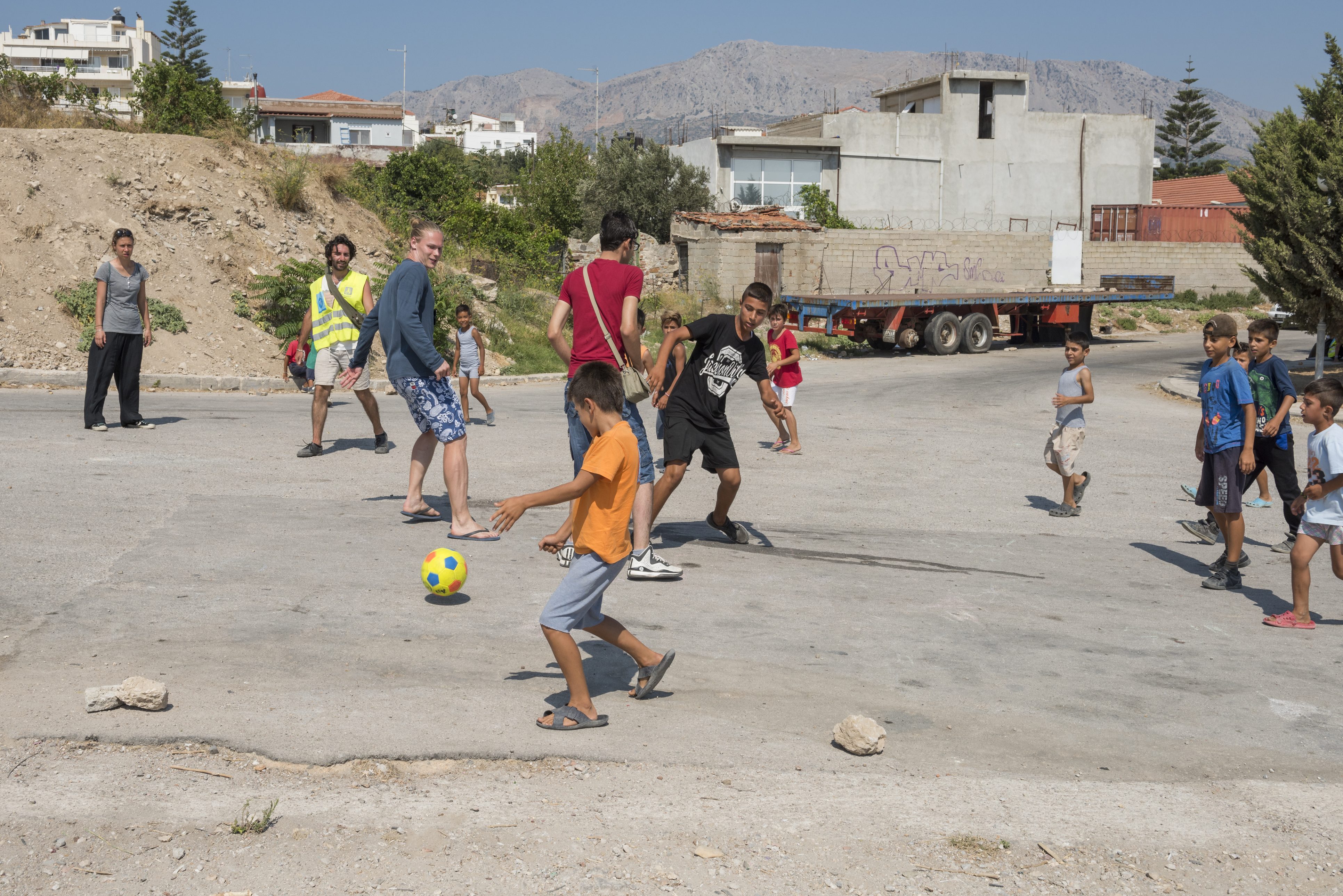 أطفال لاجئون يلعبون كرة القدم مع العاملين في مجال الإغاثة الإنسانية