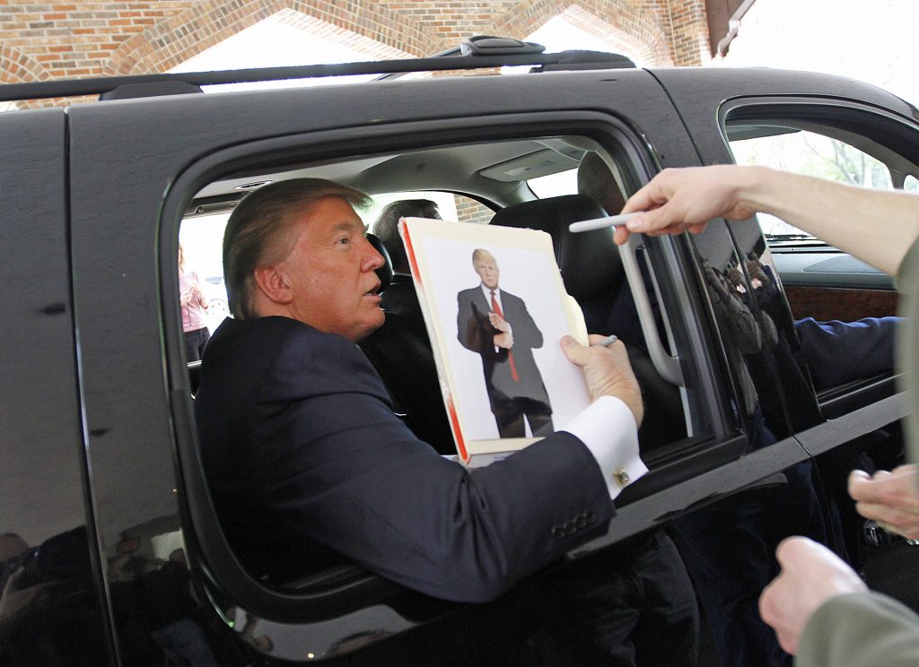 الرئيس الأمريكي دونالد ترامب حاملًا صورته (أرشيفية/ رويترز)