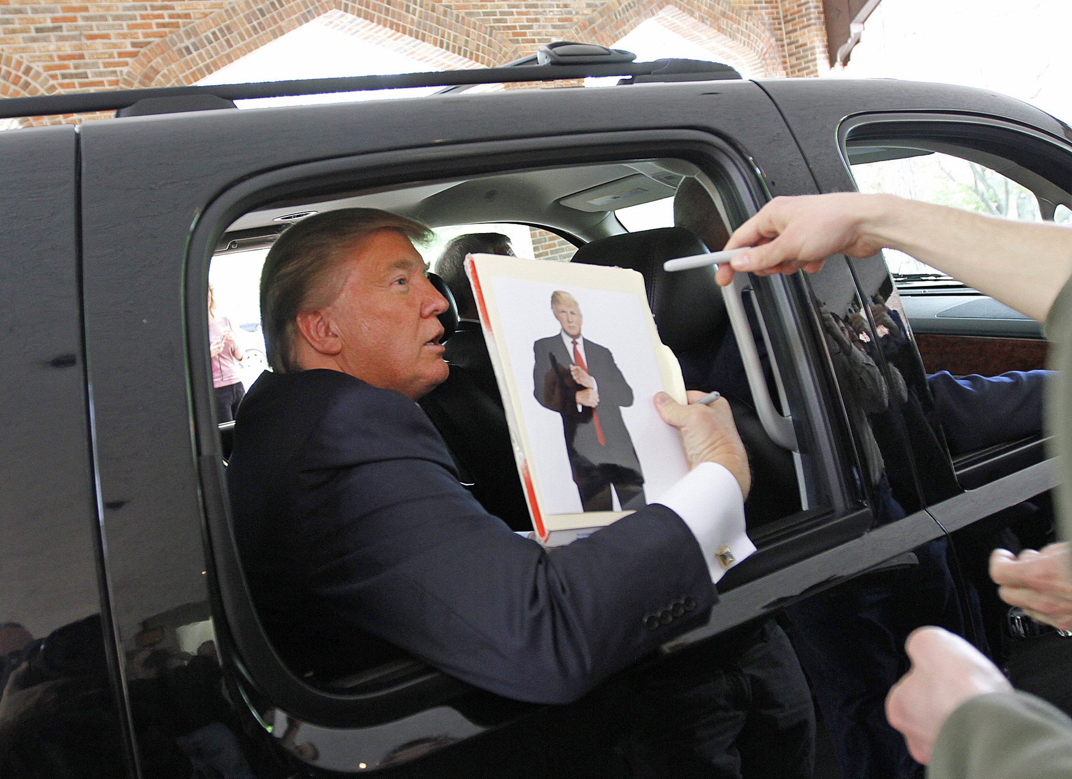 الرئيس الأمريكي دونالد ترامب حاملًا صورته (أرشيفية/ رويترز)