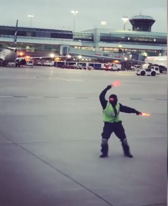 عامل في مطار يرقص بعصاه المضيئة على مدرج الإقلاع لإسعاد طفلة باكية على الطائرة التي كان يوجهها (فيديو)