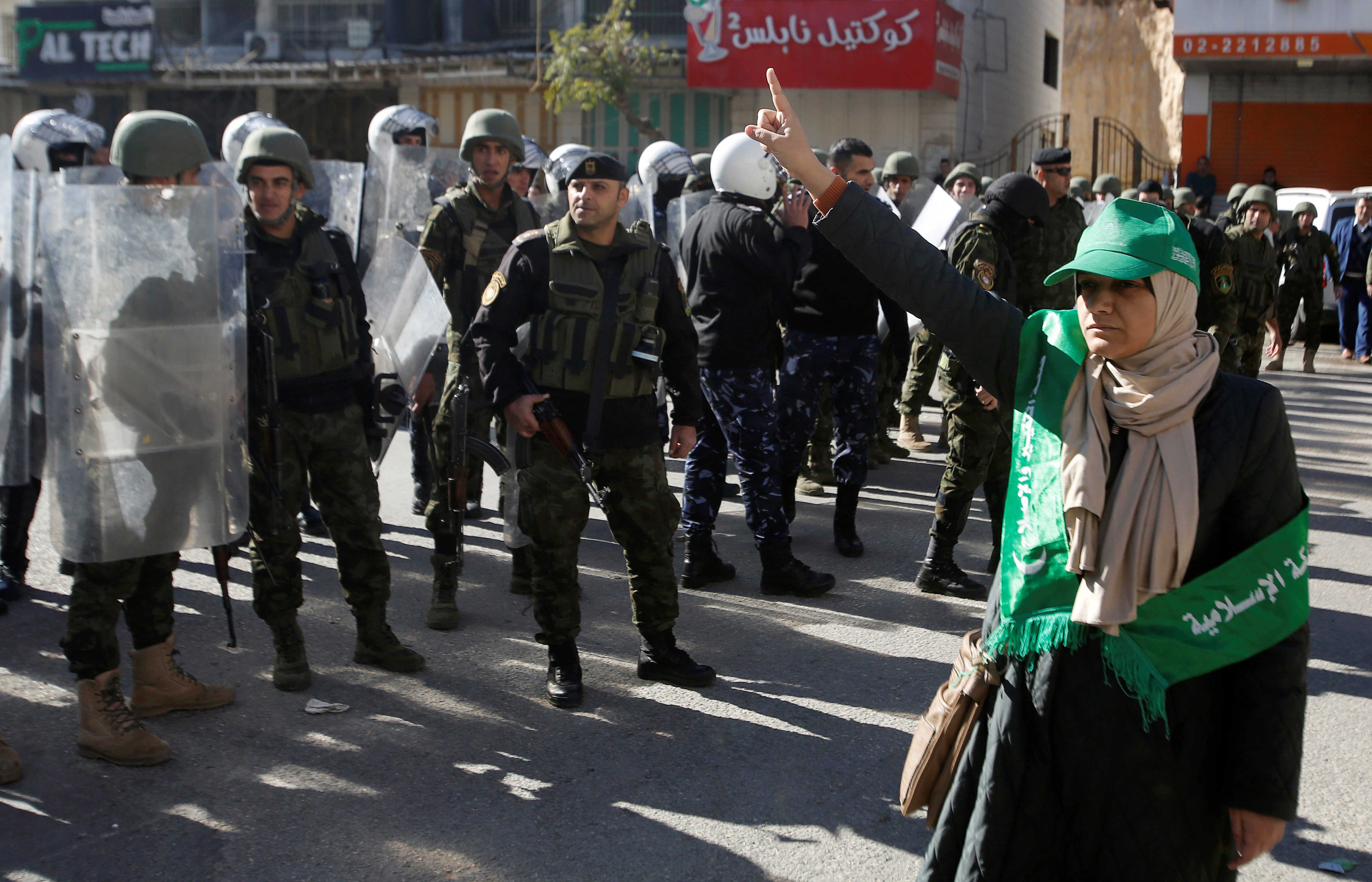 سيدة فلسطينية أمام قوات أمن السلطة خلال تظاهرة لحماس بالخليل/ رويترز