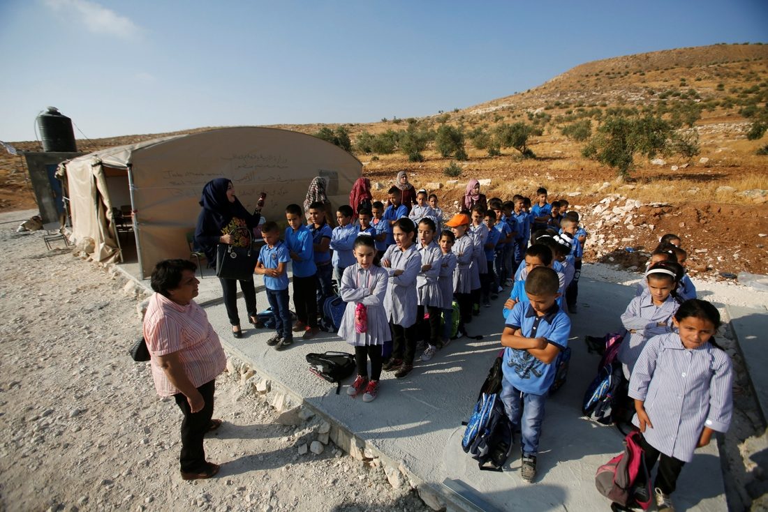 أطفال فلسطينيون يقفون في طابور خارج خيمة حيث يحضرون دروساً في قرية جبة الذيب في الضفة الغربية/ رويترز 