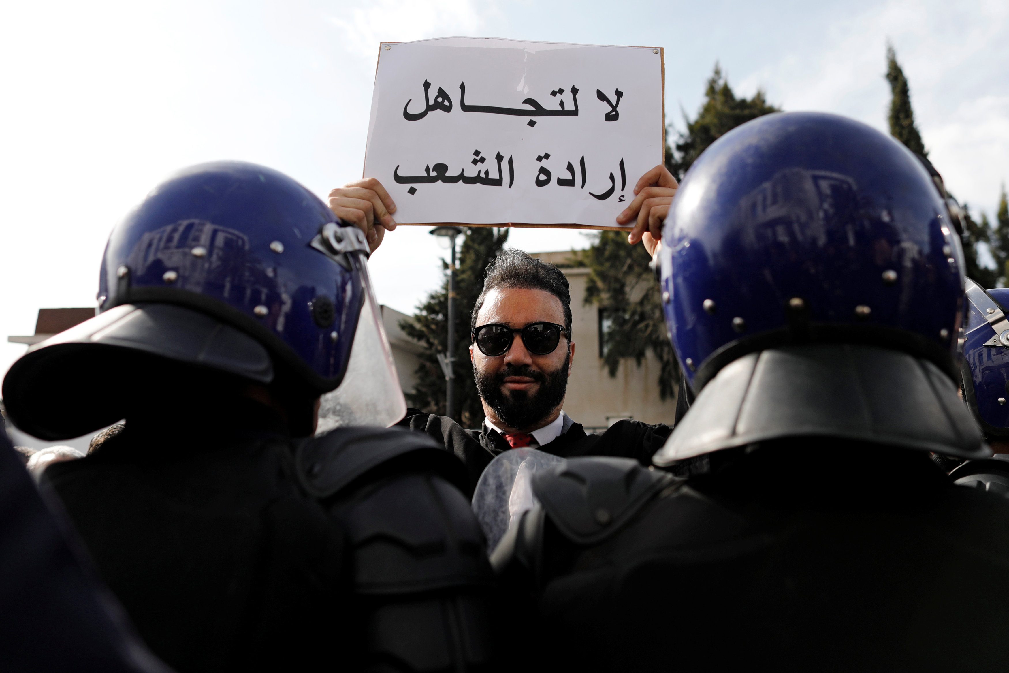 متظاهر جزائري يرفع لافته في وجه قوات الأمن/ رويترز