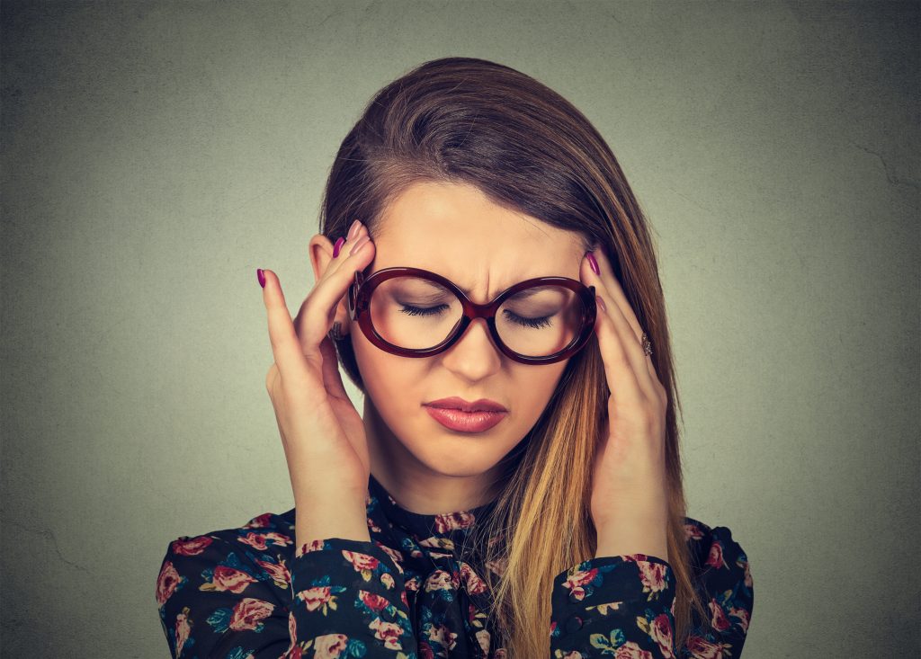 أمرأة تمسك برأسها تعاني من الضغط الذهني