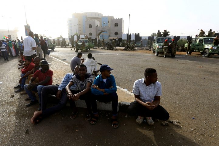 معتصمون سودانيون يجلسون أمام مقر القيادة العامة للجيش بعد إعلان تنحية البشير/ رويترز