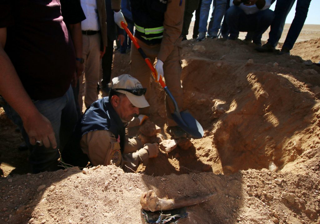 أعضاء من الدفاع المدني العراقي يفحصون المقبرة