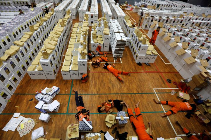 عمال يفترشون الأرض خلال عملهم في الانتخابات الأندونيسية/ رويترز