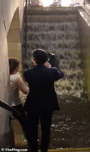 امرأة تحمل رجلاً على ظهرها في محطة قطارات حتى لا يبتل حذاؤه من مياه الأمطار