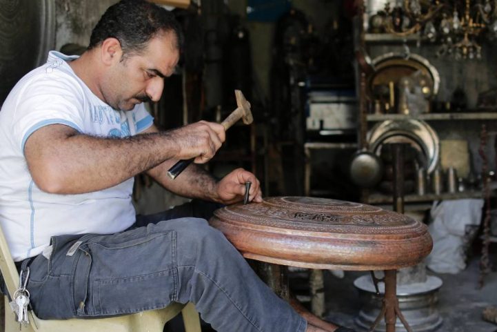 أحمد غزول يعمل على قطعة من النحاس في سوق النحاس الذي تم تجديده حديثًا في حلب/ AP