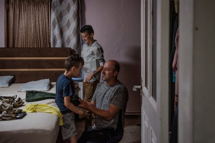 سيد أحمد يساعد ابنه حمزة على ارتداء ملابس المدرسة/ nytimes