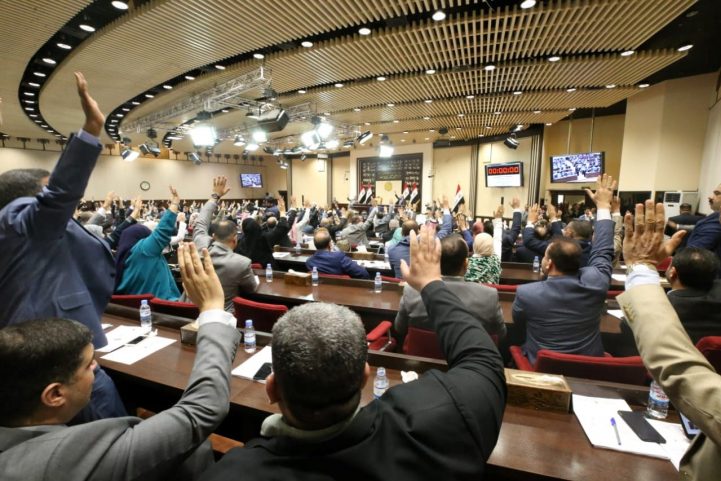 أعضاء البرلمان العراقي في جلسة يرفعون أيديهم في التصويت يوم 24 يونيو (رويترز)
