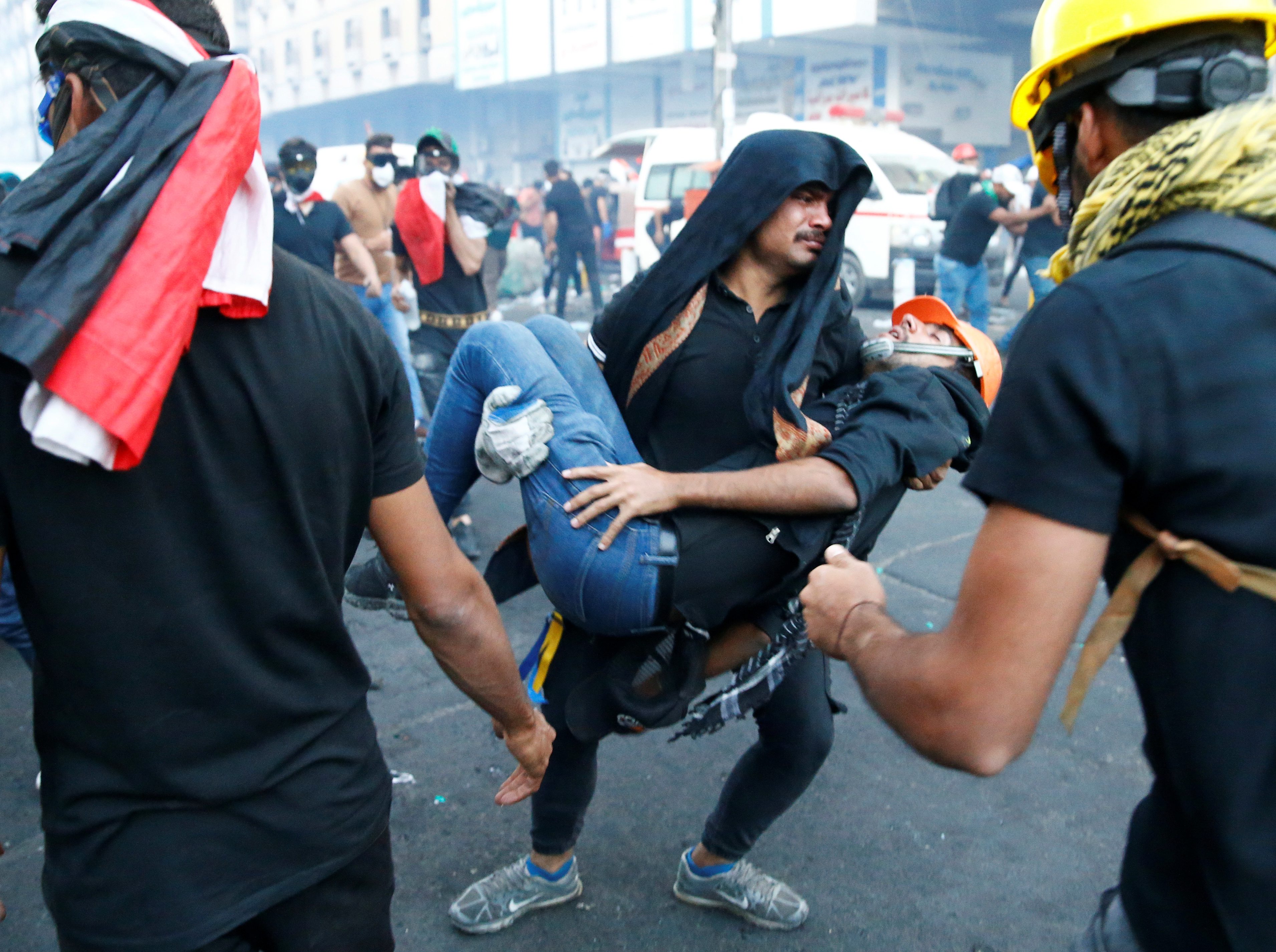 متظاهر يحمل رجلاً مصاباً خلال الاحتجاجات المستمرة المناهضة للحكومة في بغداد