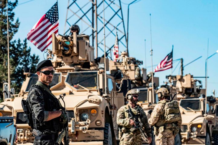 عضو في وحدات حماية الشعب الكردي (YPG) يقف إلى جانب عربات مدرعة أمريكية أمام بئر نفطي في محافظة الحسكة شمال شرق سوريا/ Getty