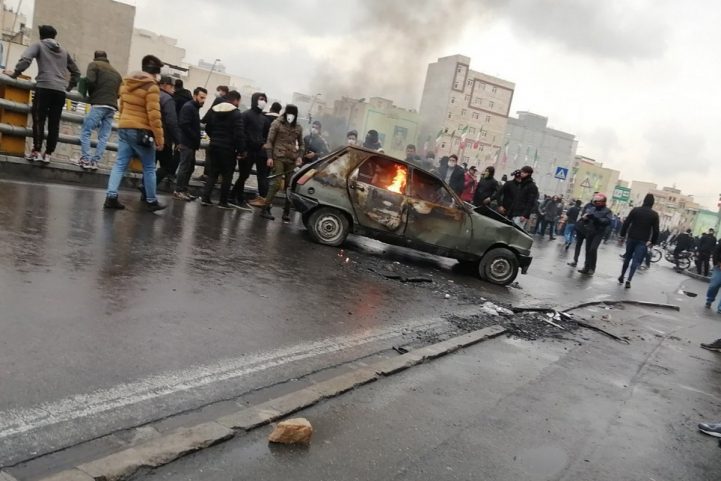 متظاهرون ايرانيون يقفون حول سيارة اشتعلت فيها النيران خلال اشتباكات عقب ارتفاع أسعار الوقود في طهران/ EPA