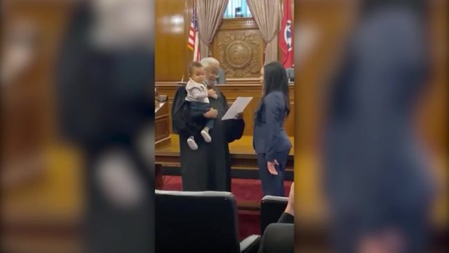 قاضٍ يحمل رضيعاً بينما تؤدي والدته قسم المحاماة أثناء التخرج في الجامعة