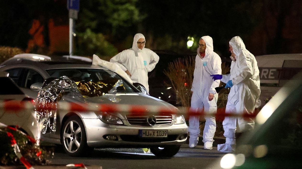 خبراء الطب الشرعي حول سيارة تالفة بعد إطلاق نار في هاناو بالقرب من فرانكفورت/رويترز