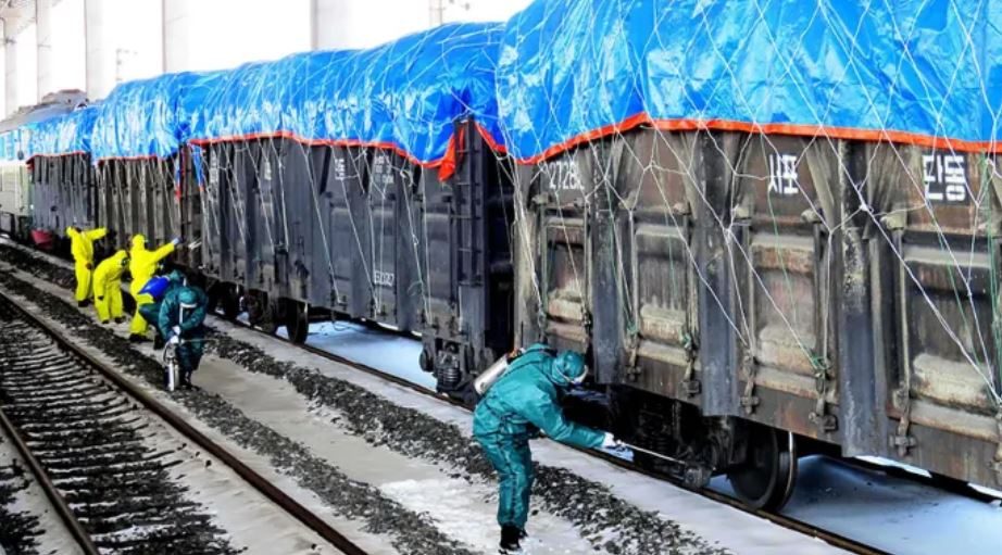 عمال كوريون شماليون يقومون بتعقيم قطار شحن