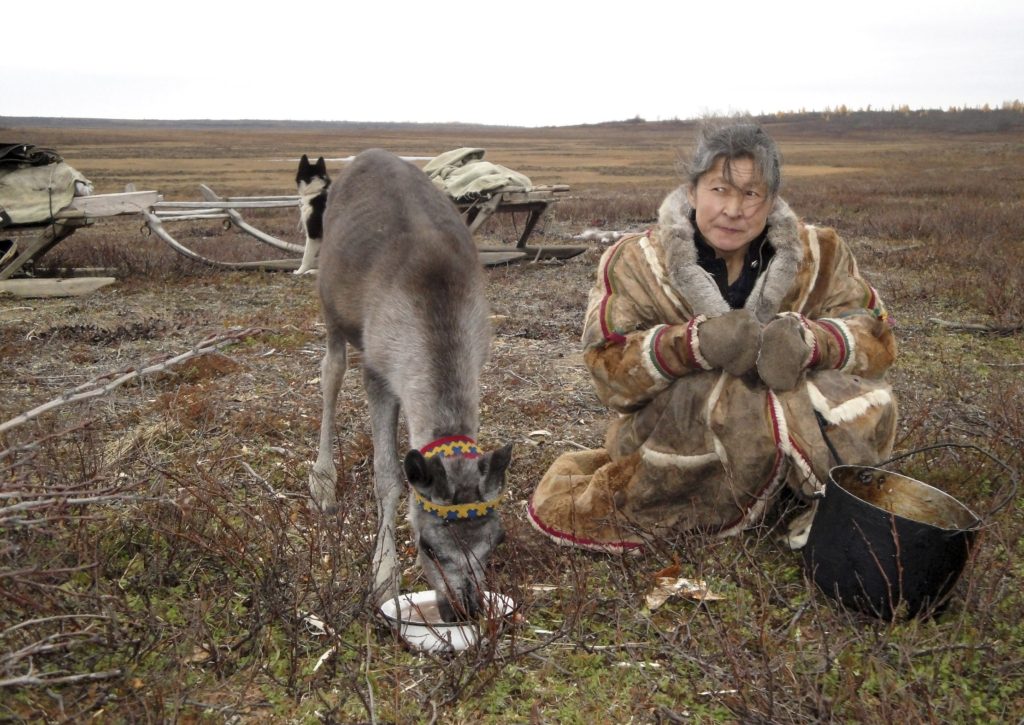 مقيم محلي مع غزال يتغذى على شبه جزيرة ياما ، شمال الدائرة القطبية/رويترز