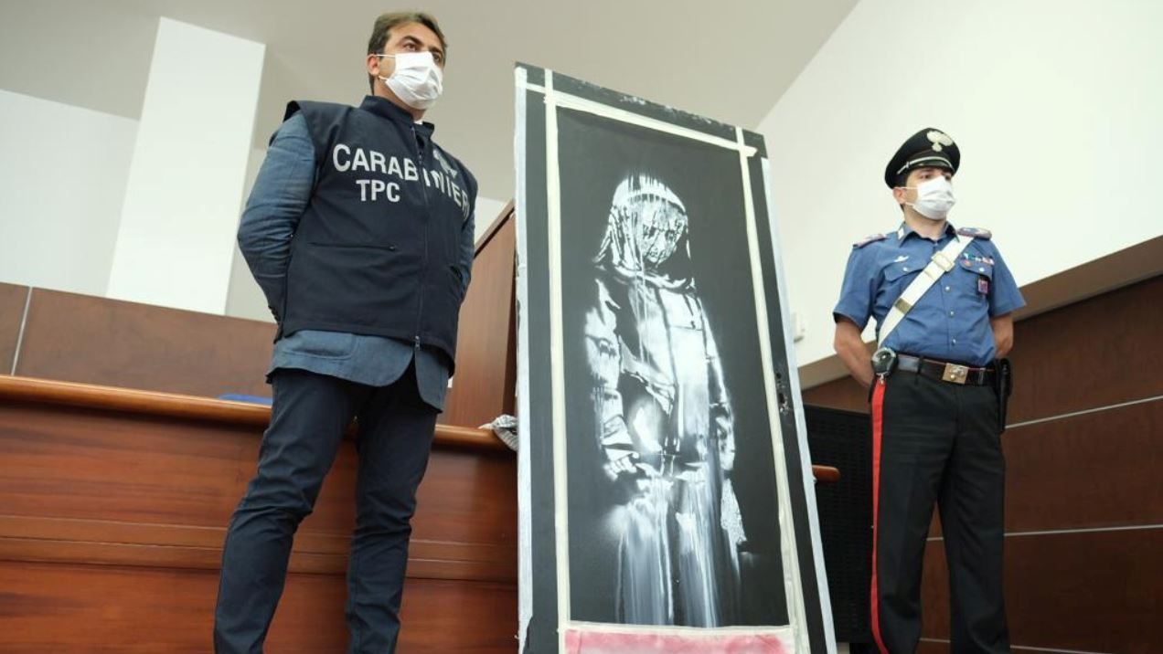 جدارية سيدة تغطي غلالة رقيقة وجهها وتطرق حزينة بعينيها إلى الأرض