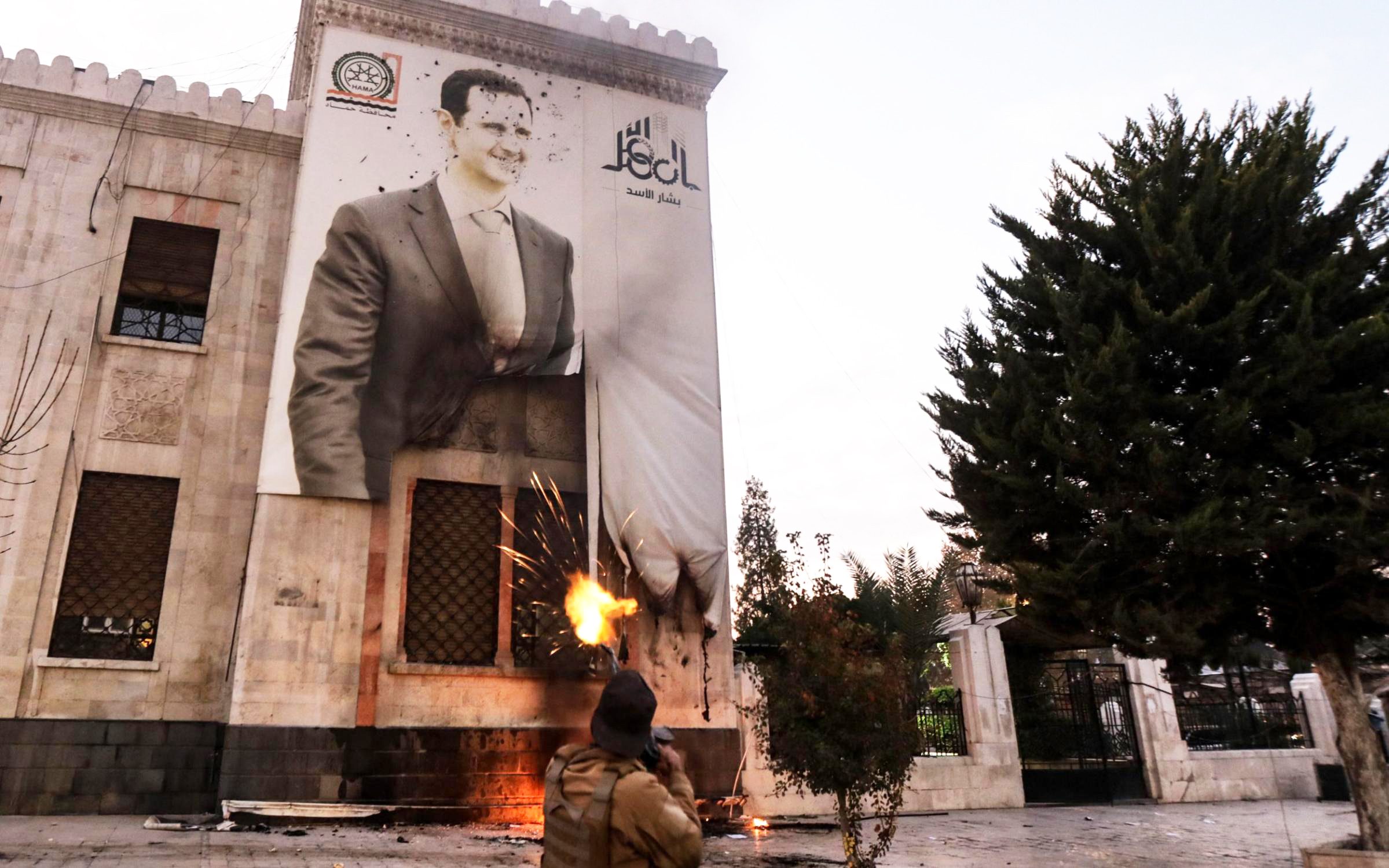 مقاتلون من المعارضة يطلقون النار على ملصق لبشار الأسد في حماة، رويترز